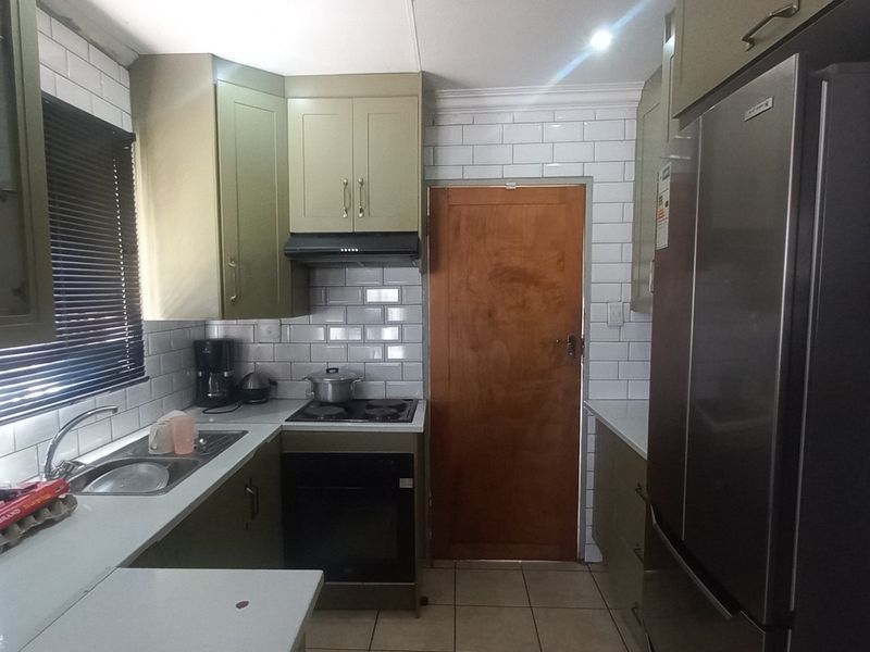 A functional kitchen featuring olive-toned cabinetry, white subway tile backsplash, built-in oven with hob, and tiled flooring.