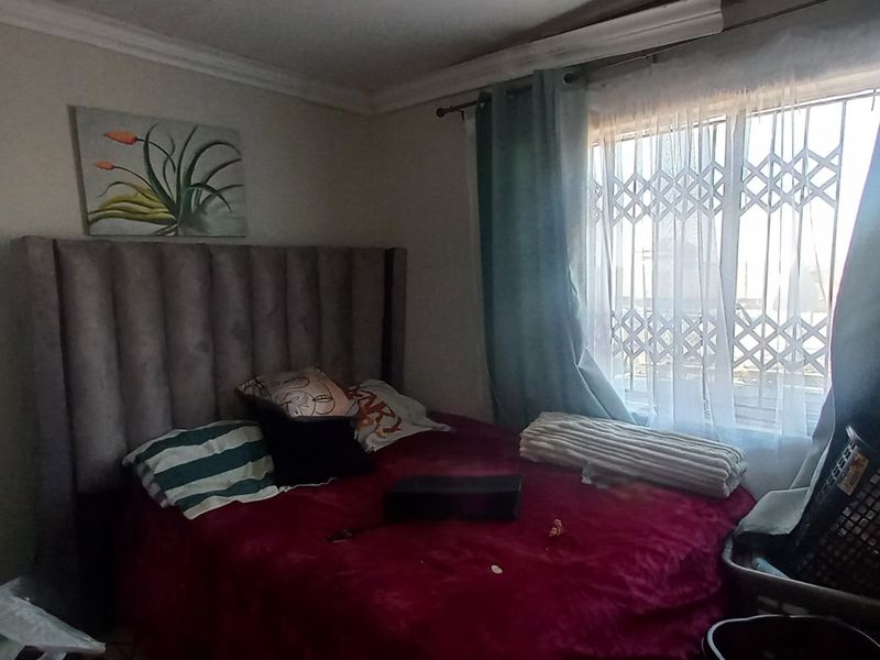 A bedroom featuring a window with a security gate and built-in wardrobe storage.