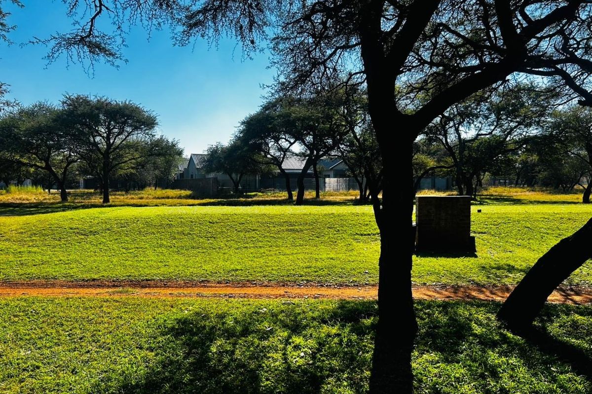 A spacious, well-maintained residential plot featuring established trees and a level lawn area, suitable for future development.