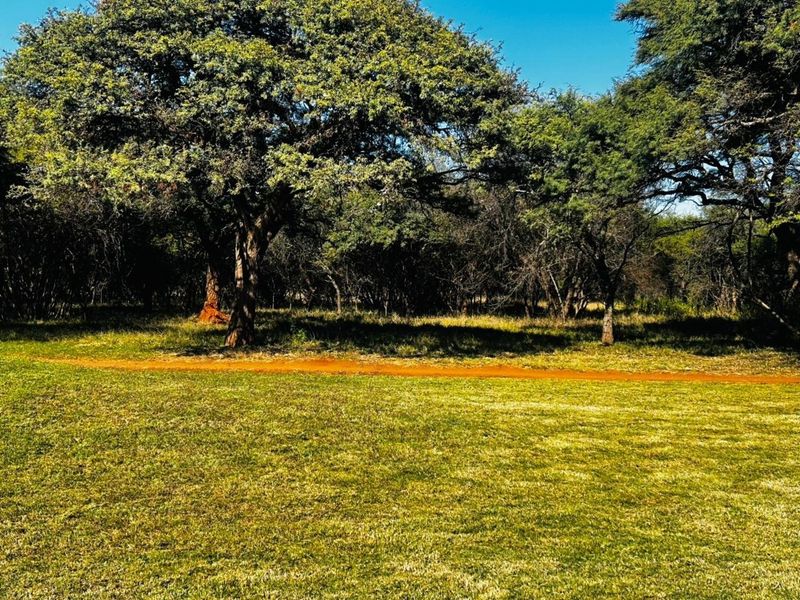 A view of a well-maintained grassy area featuring mature trees, suitable for residential development.