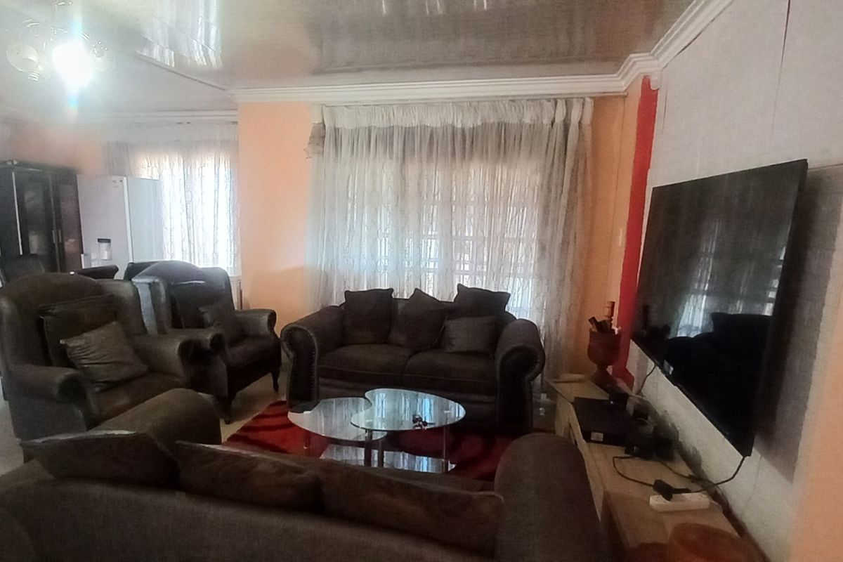 A living room featuring tiled flooring, coved ceilings, and sliding glass doors providing access to the exterior.