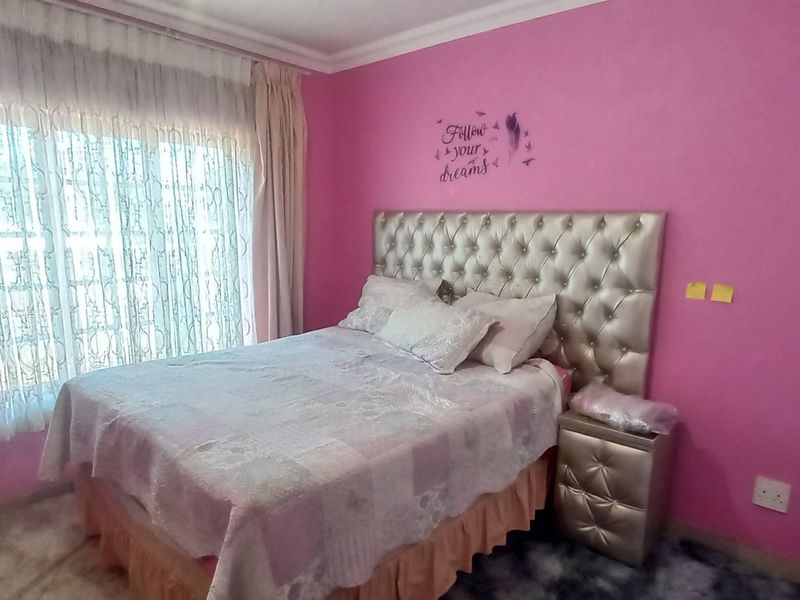 A bedroom featuring built-in cupboards, coving, and large windows with curtains, providing a functional space with potential for aesthetic updates.