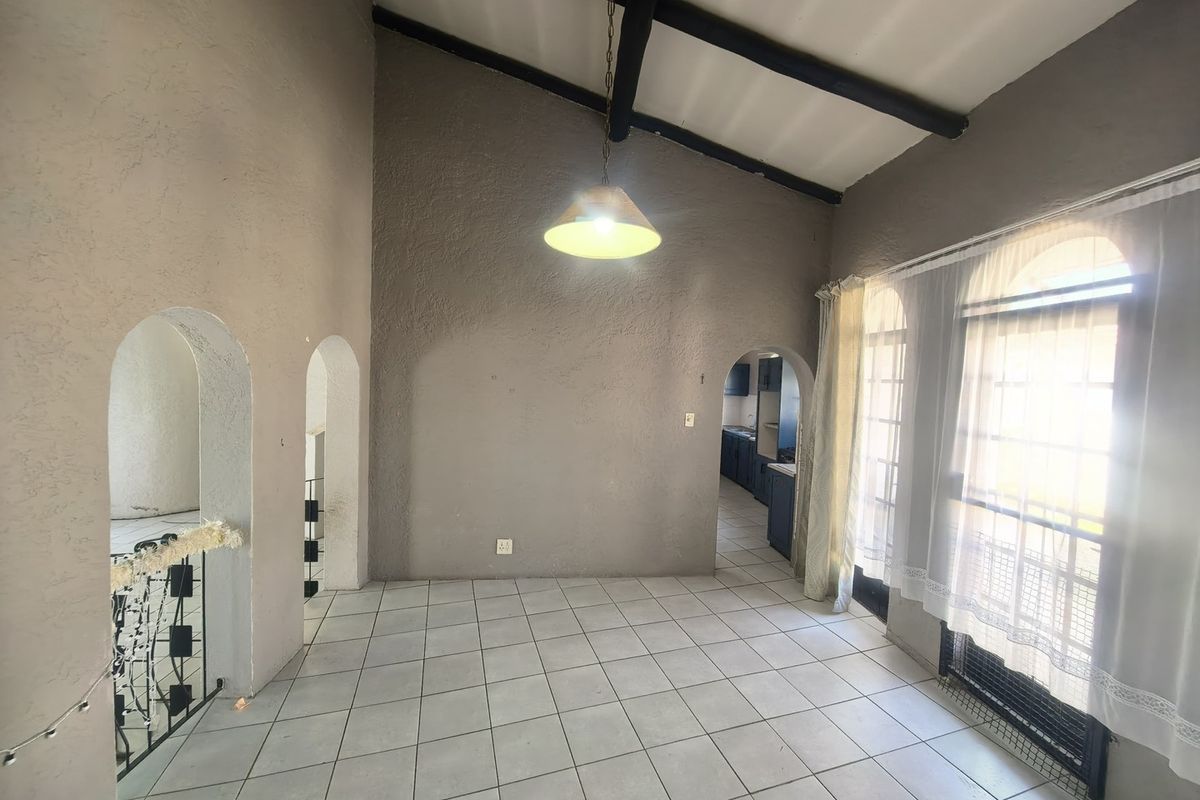 Spacious living area featuring high vaulted ceilings with exposed timber beams, tiled flooring, and distinctive arched architectural details leading to adjacent rooms.