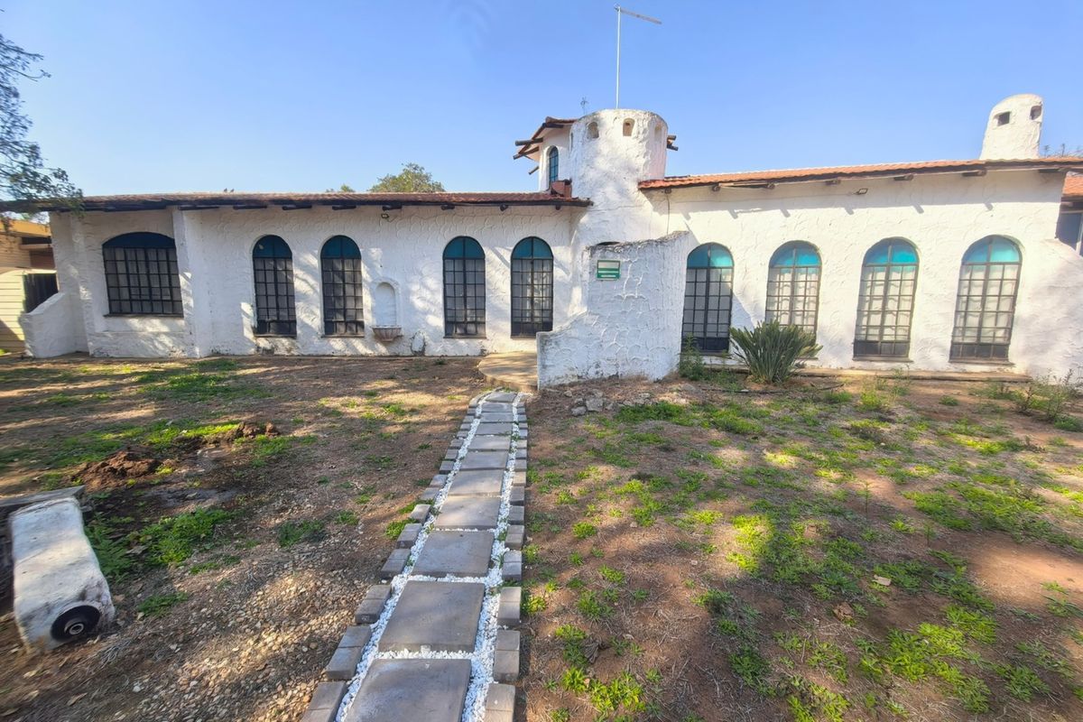 Rear elevation of a unique property featuring a turret, arched windows, and a stone pathway leading to the main structure.