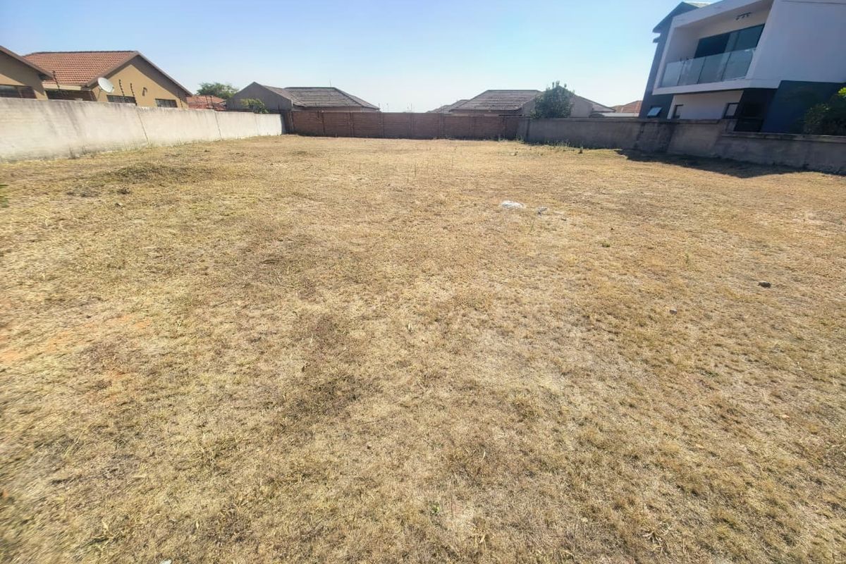 A vacant residential plot featuring level ground and enclosed by perimeter boundary walls, situated in a developed neighborhood.