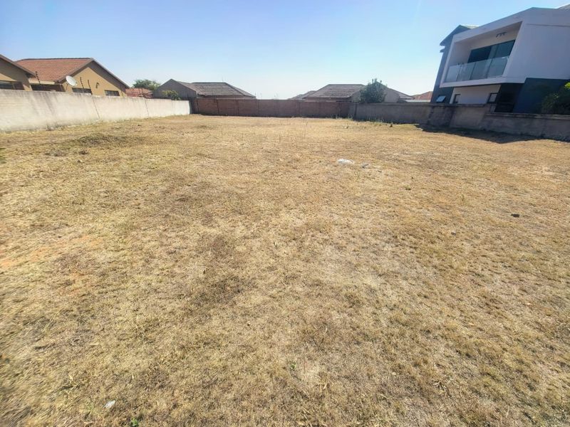 A vacant residential plot featuring level ground and enclosed by perimeter boundary walls, situated in a developed neighborhood.