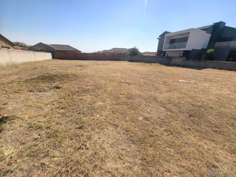 A vacant residential plot of land enclosed by perimeter boundary walls, offering a blank canvas for new construction in a developed neighborhood.