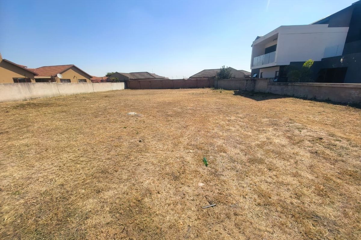 A vacant residential plot featuring perimeter boundary walls, offering a clear space ready for development in an established neighborhood.