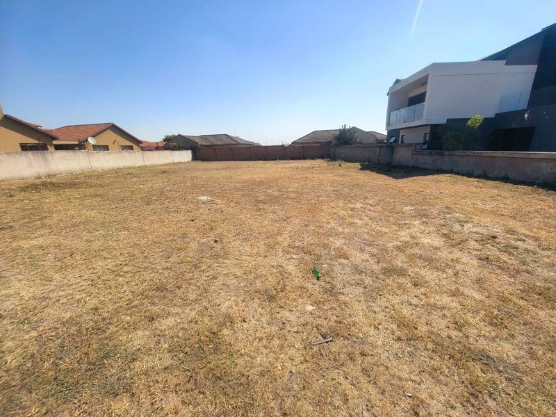 A vacant residential plot featuring perimeter boundary walls, offering a clear space ready for development in an established neighborhood.