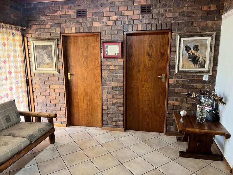 A living area featuring exposed brick walls, ceramic floor tiles, and two timber veneer doors.