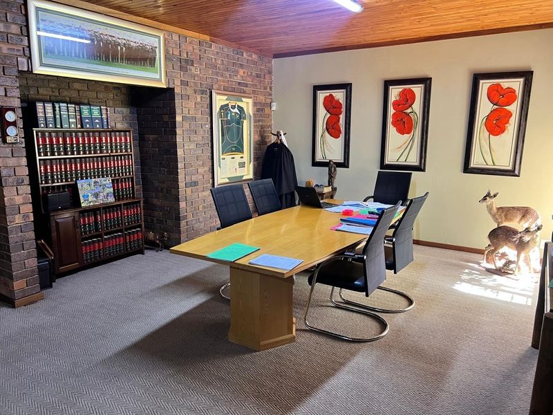 A spacious home office featuring a distinctive exposed brick wall, warm timber ceiling, and built-in shelving, providing a professional and character-filled workspace.