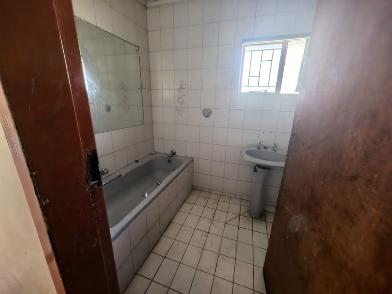 A dated bathroom featuring a bathtub, pedestal basin, and tiled finishes, requiring modernization to improve its overall condition and appeal.