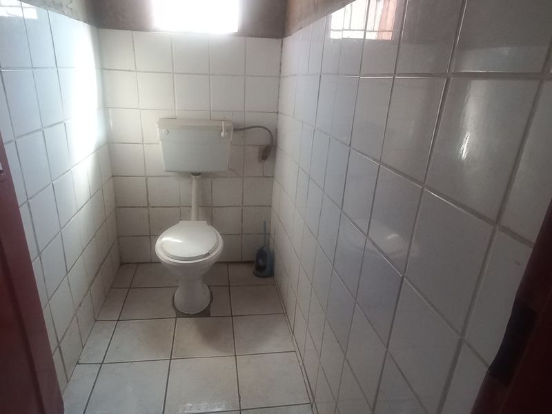 A compact, tiled bathroom featuring a standard toilet and cistern, requiring cosmetic updates to improve the overall finish and condition.