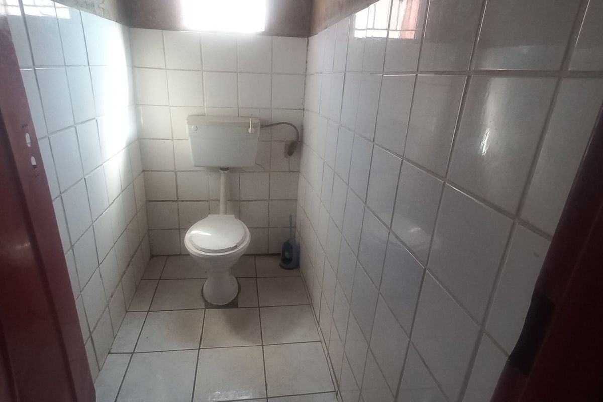 A compact, tiled bathroom featuring a standard toilet and cistern, requiring cosmetic updates to improve the overall finish and condition.