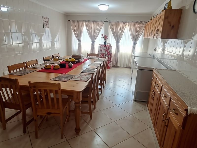Spacious dining area featuring tiled walls, ceramic floor tiles, and built-in wooden cabinetry providing ample storage space.