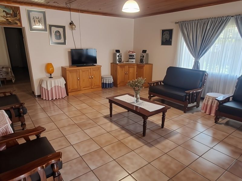 Spacious living room featuring tiled flooring and a timber tongue and groove ceiling, offering a comfortable and functional layout.