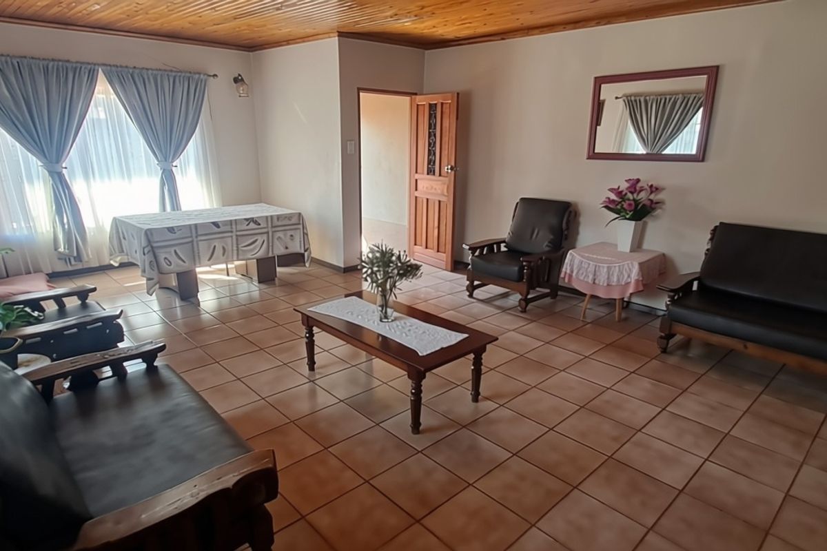 Spacious living room featuring tiled flooring and a timber-paneled ceiling, offering a traditional layout with direct access to adjacent rooms.