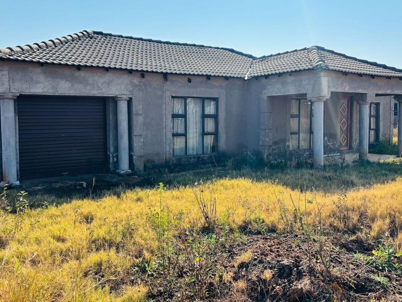 Front elevation of a single-story house featuring a tiled roof, integrated garage, and concrete columns, set on a large plot with overgrown landscaping.