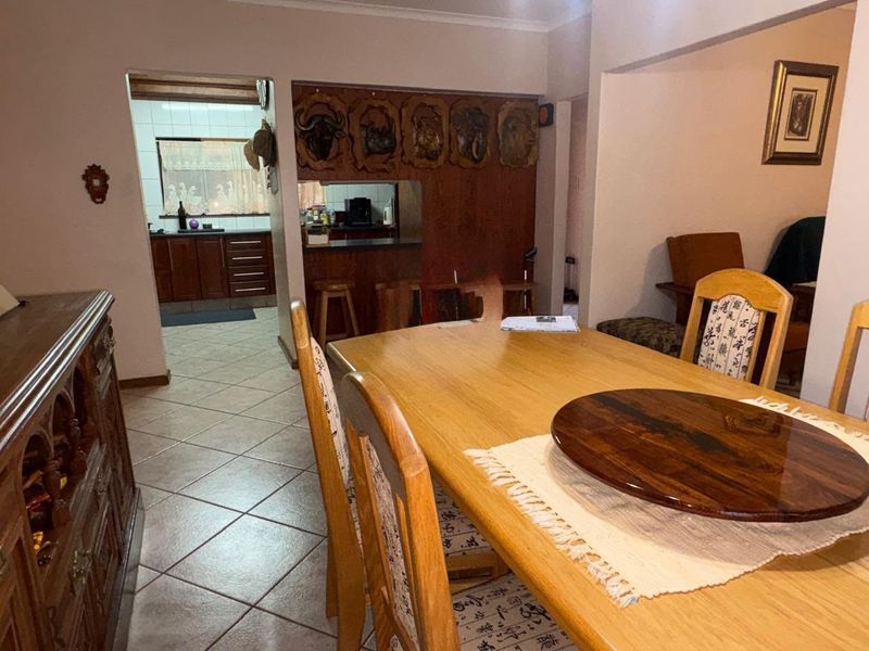Open plan dining area featuring tiled flooring and a pass-through window connecting to the kitchen with built-in cabinetry.