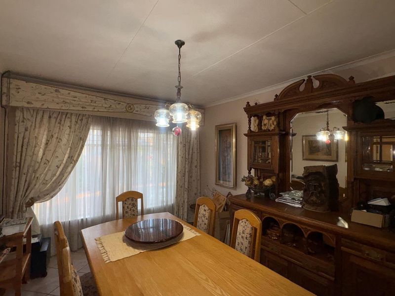 A traditional dining room featuring tiled flooring, a central light fixture, and a decorative curtain pelmet over the window.