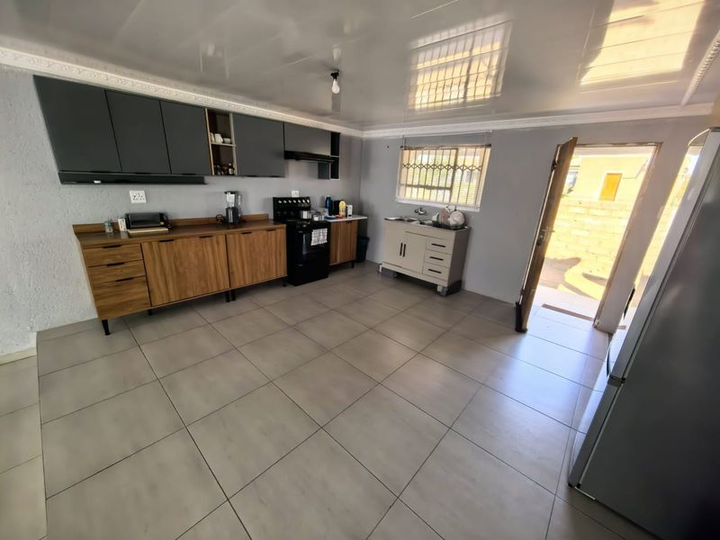 A functional kitchen featuring two-tone cabinetry, a built-in stove with extractor, tiled flooring, and direct access to the exterior.