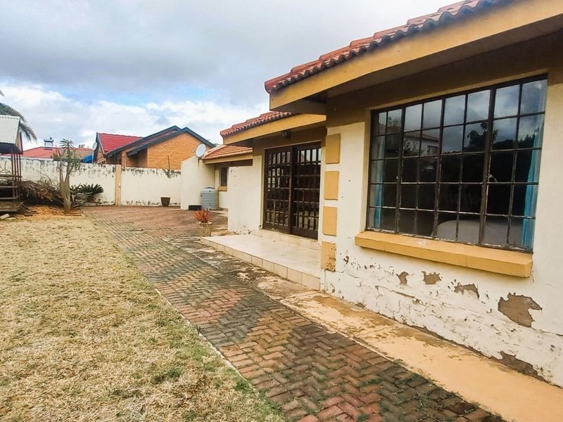Rear view of the property featuring a paved patio area, sliding door access, and a garden with a detached wooden structure.