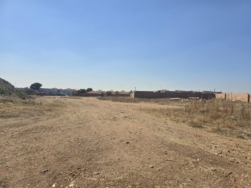 A vacant residential plot of land featuring a level surface and perimeter brick walling, offering a blank canvas for future development.