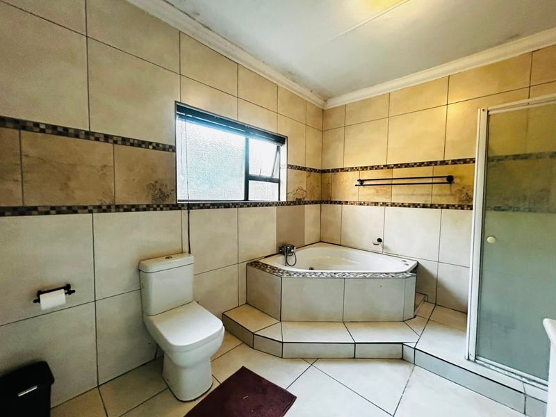 A dated bathroom featuring a corner bathtub, separate shower enclosure, and tiled finishes, requiring cosmetic updates to improve its overall condition and appeal.