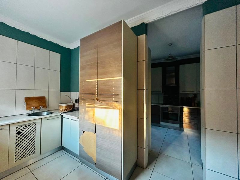 A kitchen area featuring tiled surfaces and built-in cabinetry, showing visible wear and damage to the cabinet finish.