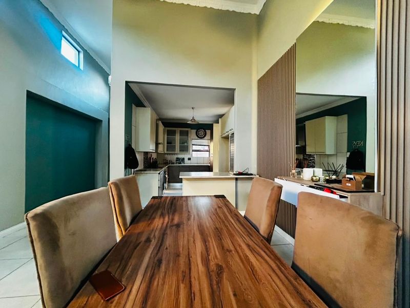 Open plan dining area featuring tiled floors and decorative wall paneling, leading into a functional kitchen with built-in cabinetry and a central island.