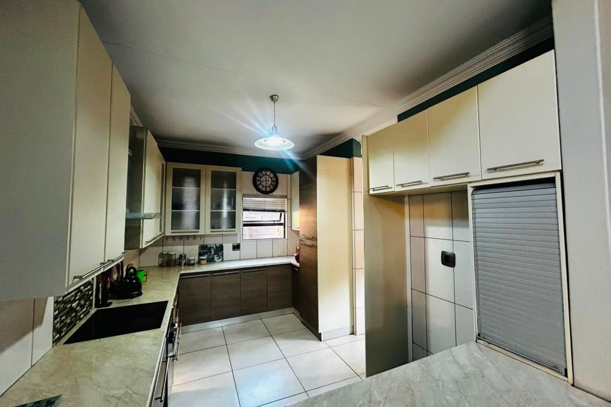 A functional kitchen featuring ample built-in cabinetry, laminate countertops, tiled flooring, and integrated appliances, offering a clean and well-maintained workspace.