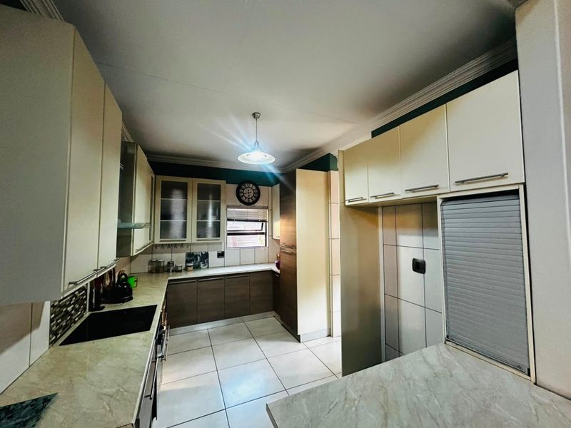 A functional kitchen featuring ample built-in cabinetry, laminate countertops, tiled flooring, and integrated appliances, offering a clean and well-maintained workspace.