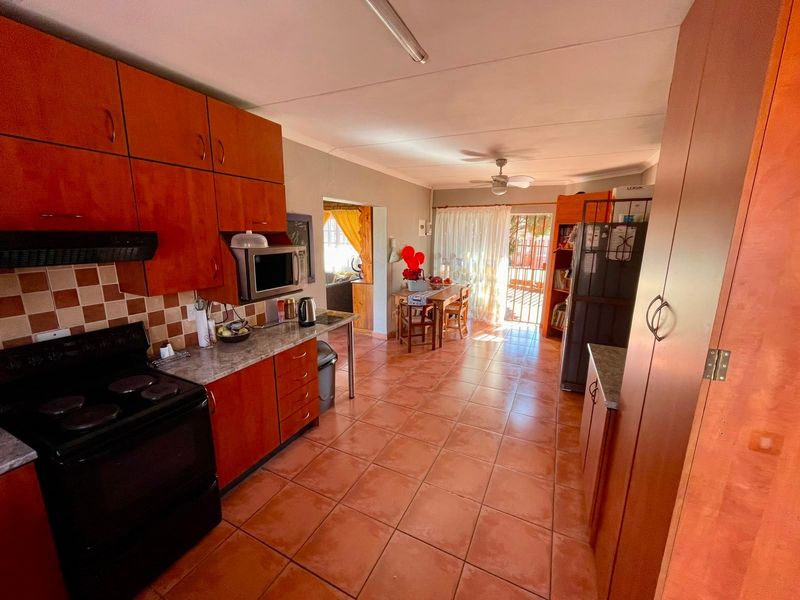 Open-plan kitchen and dining area featuring wooden cabinetry, tiled flooring, and direct access to the outdoor patio space.