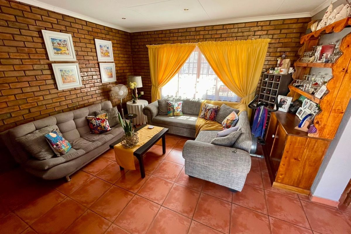 A living room featuring exposed brick walls, terracotta floor tiles, and recessed downlighting, offering a warm and rustic aesthetic.