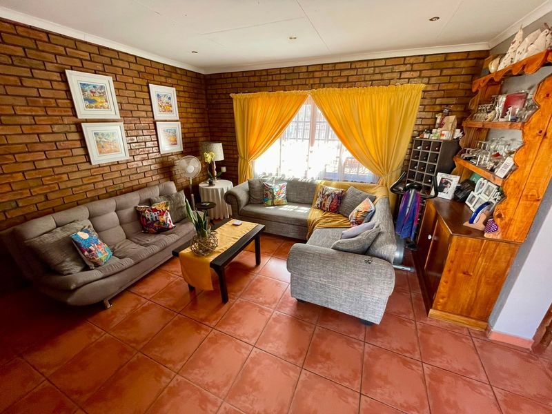 A living room featuring exposed brick walls, terracotta floor tiles, and recessed downlighting, offering a warm and rustic aesthetic.