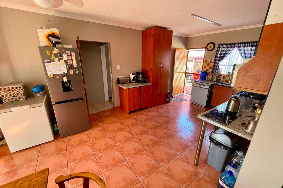A functional kitchen featuring tiled flooring, built-in wooden cabinetry, laminate countertops, and direct access to the exterior.