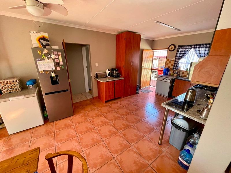 A functional kitchen featuring tiled flooring, built-in wooden cabinetry, laminate countertops, and direct access to the exterior.