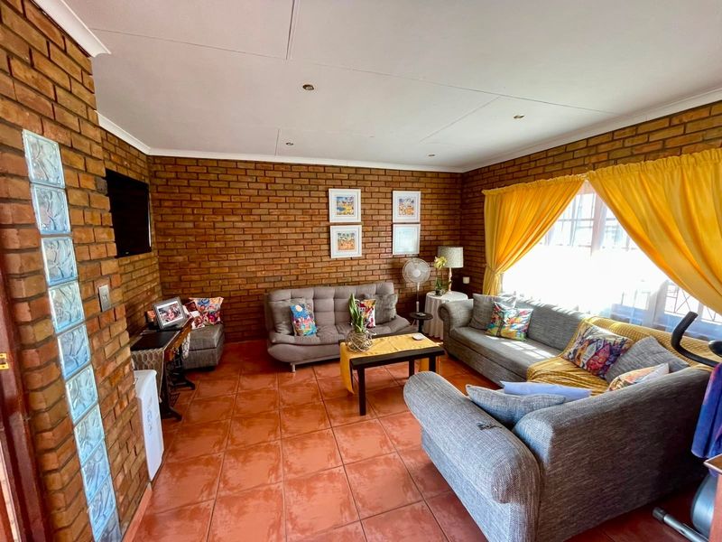 A living room featuring exposed brick walls, terracotta floor tiles, and a unique glass block feature wall, providing a rustic and textured aesthetic.