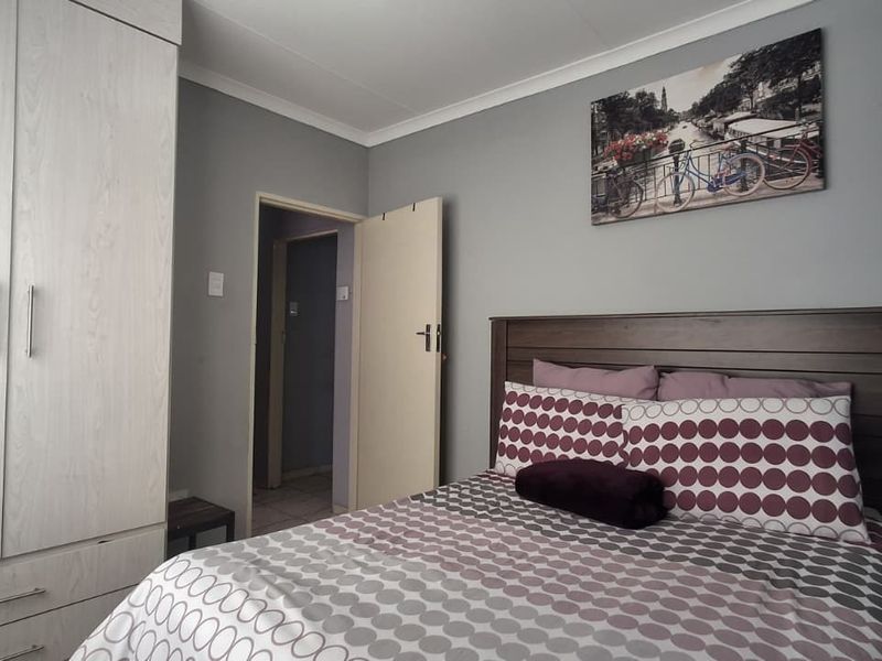 A well-maintained bedroom featuring a neutral grey color palette, built-in wardrobe storage, and coved ceiling detailing.