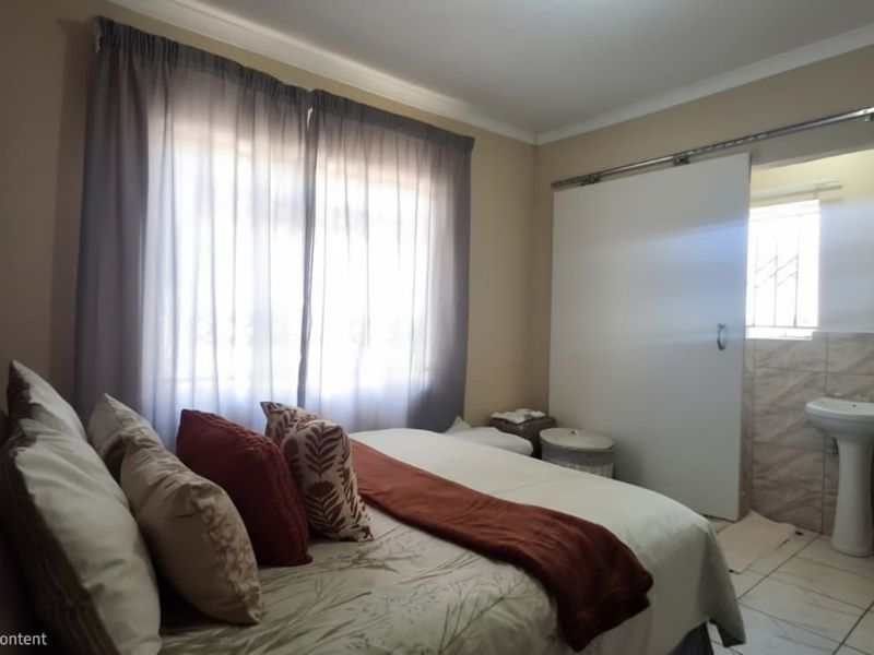 A bedroom featuring a sliding door leading to an en-suite bathroom with a pedestal basin and tiled flooring.