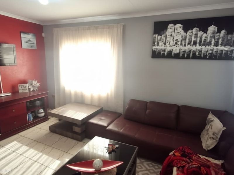 A living room featuring tiled flooring and a feature wall, providing a functional space for relaxation.