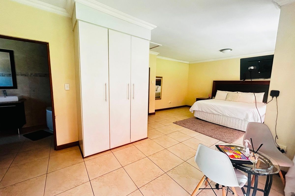 Spacious bedroom featuring tiled flooring, built-in cupboards, crown molding, and direct access to an en-suite bathroom.