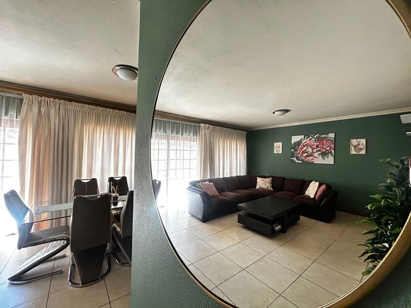 Spacious open-plan living and dining area featuring tiled flooring, large windows with curtains, and direct access to the exterior through sliding glass doors.
