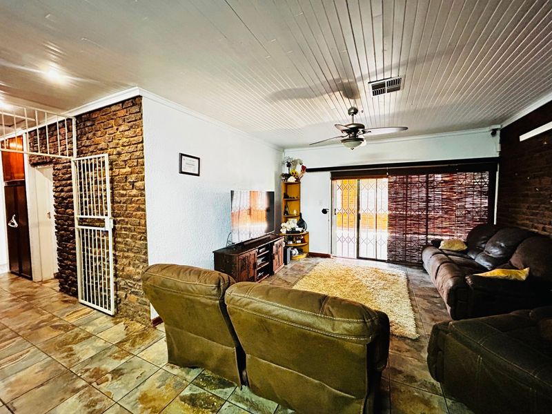 Living room featuring exposed brick wall, tiled flooring, tongue and groove ceiling, ceiling fan, and sliding glass door access to the exterior.