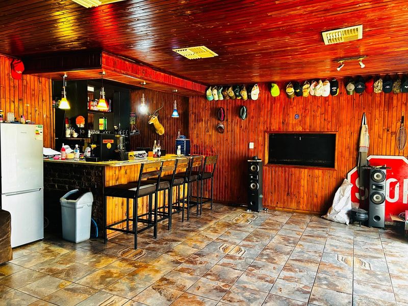 A dedicated bar area featuring timber wall and ceiling paneling, tiled flooring, and a built-in bar counter with integrated lighting.