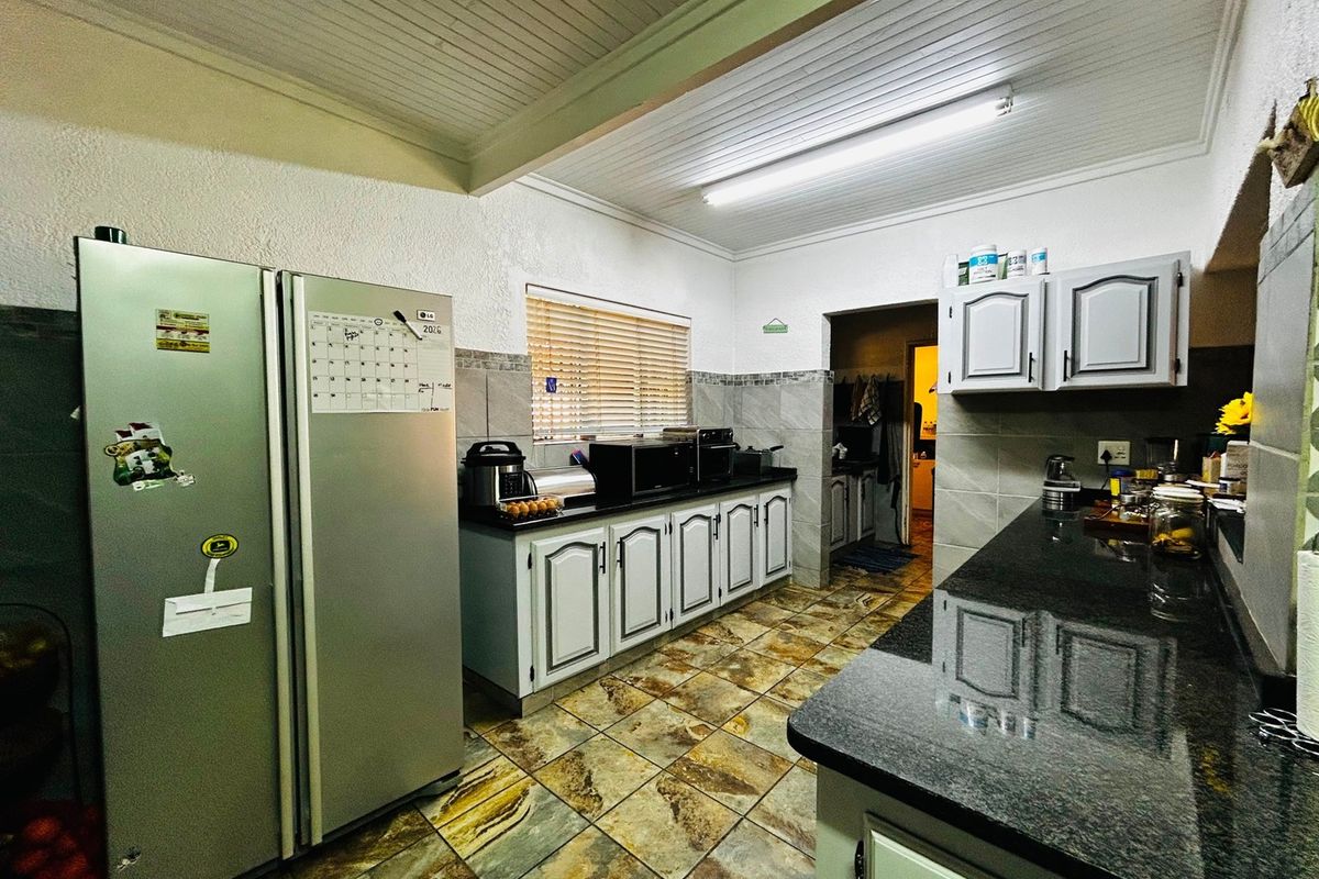 A functional kitchen featuring granite countertops, ample cabinetry, tiled flooring, and a tongue and groove ceiling with integrated lighting.