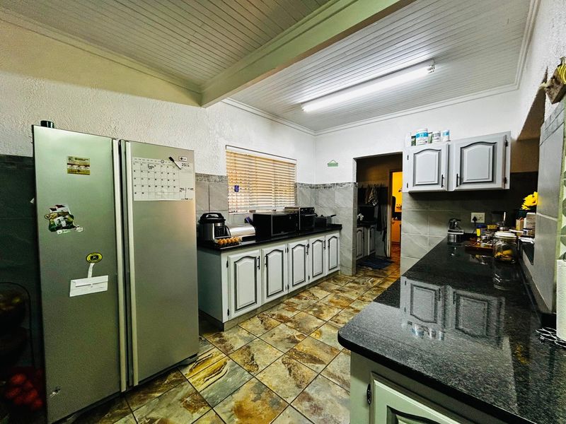 A functional kitchen featuring granite countertops, ample cabinetry, tiled flooring, and a tongue and groove ceiling with integrated lighting.