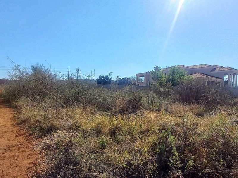Vacant residential land featuring a perimeter wall with electric fencing, currently covered in overgrown vegetation.