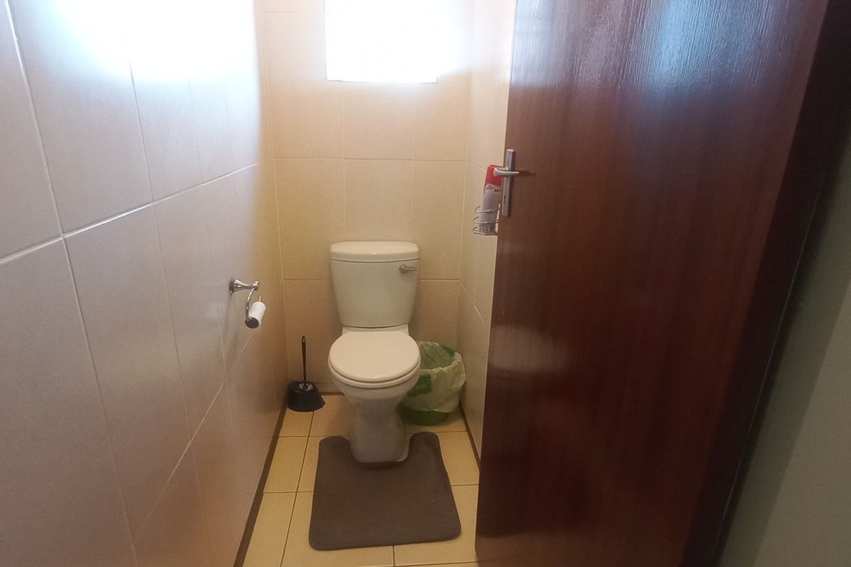 A compact, functional guest toilet featuring tiled walls and flooring, providing a clean and practical space.