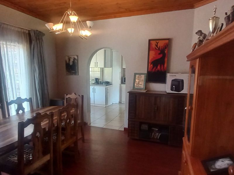 A dining room featuring a timber ceiling, arched doorway leading to the kitchen, and tiled flooring, offering a traditional layout.